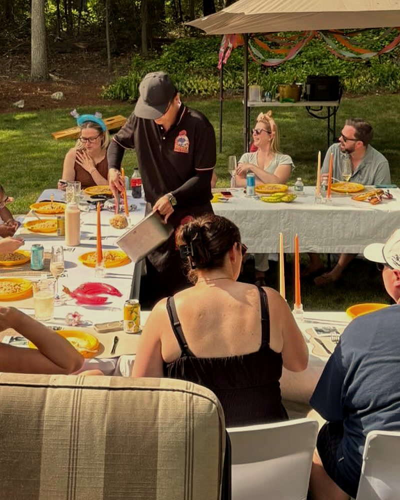 Hibachi chef serving fried rice to guests at a backyard party table